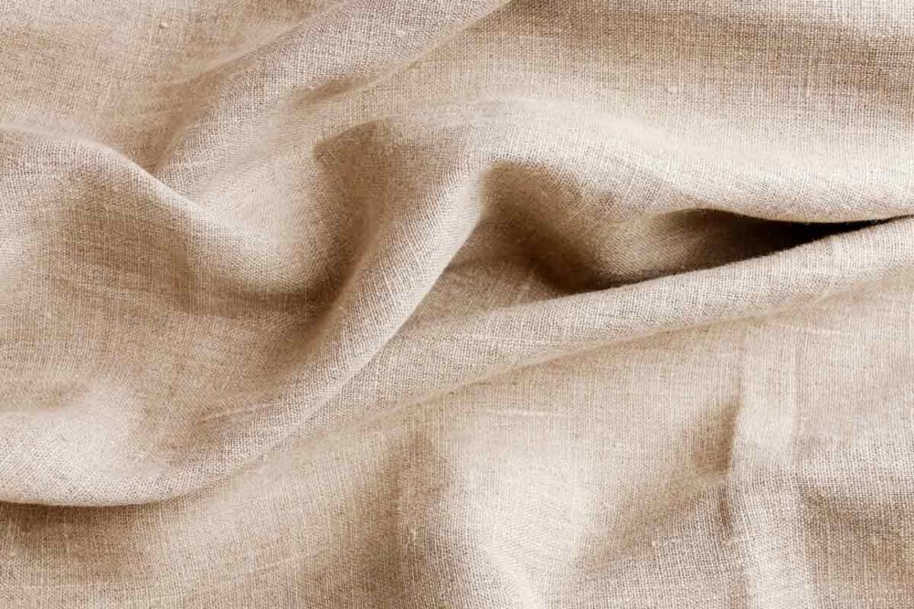 Close up beige table cloth fabric texture wallpaper background A flat lay  view of a casually wrinkled rustic beige kitchen cloth towel with as a  background image. Stock Photo